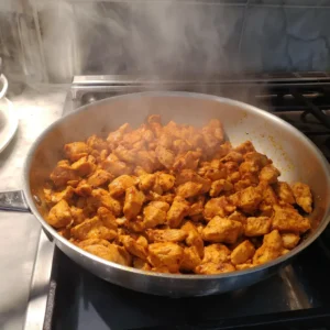 Seasoned chicken searing in a skillet for high protein buffalo chicken mac and cheese