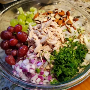 Shredded chicken, grapes, celery, red onion and almonds in a bowl for high protein chicken salad