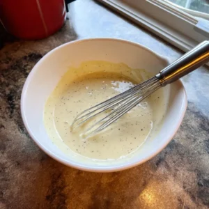 Greek yogurt dressing with Dijon and lemon whisked in a bowl for high protein chicken salad