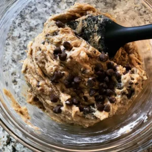 Folding thick banana protein muffin batter with a spatula until just combined