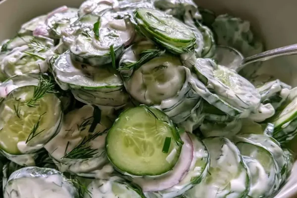 Bowl of creamy high protein cucumber salad with dill, chives and red onion