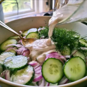 Creamy dressing stirred into sliced cucumbers to make high protein cucumber salad