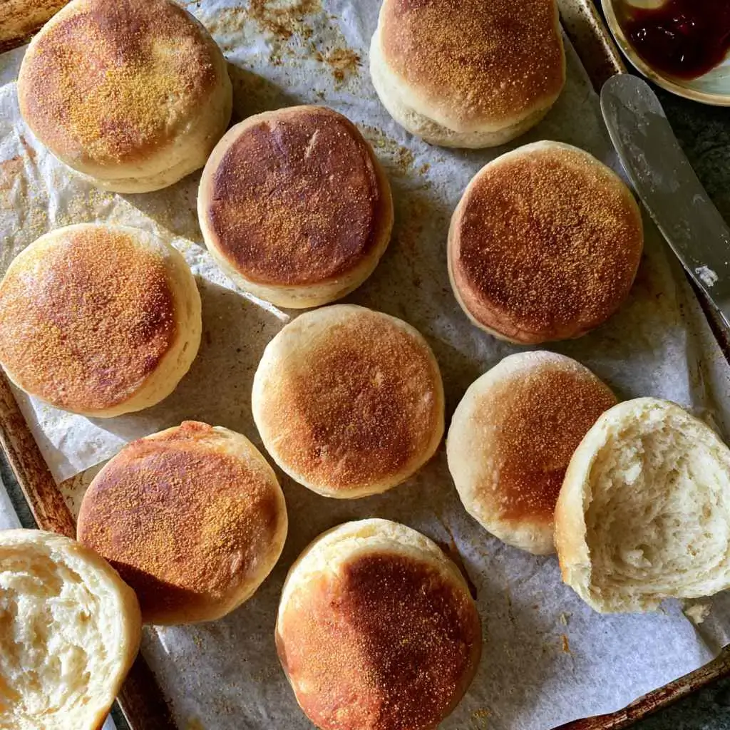 A high protein English muffin fork-split to show nooks and crannies, lightly toasted with melting butter