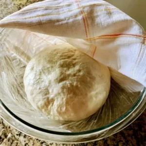 Risen, doubled high protein english muffin dough in a glass bowl