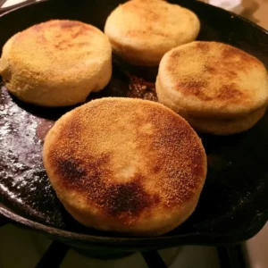 High protein english muffins cooking golden on a dry cast-iron skillet