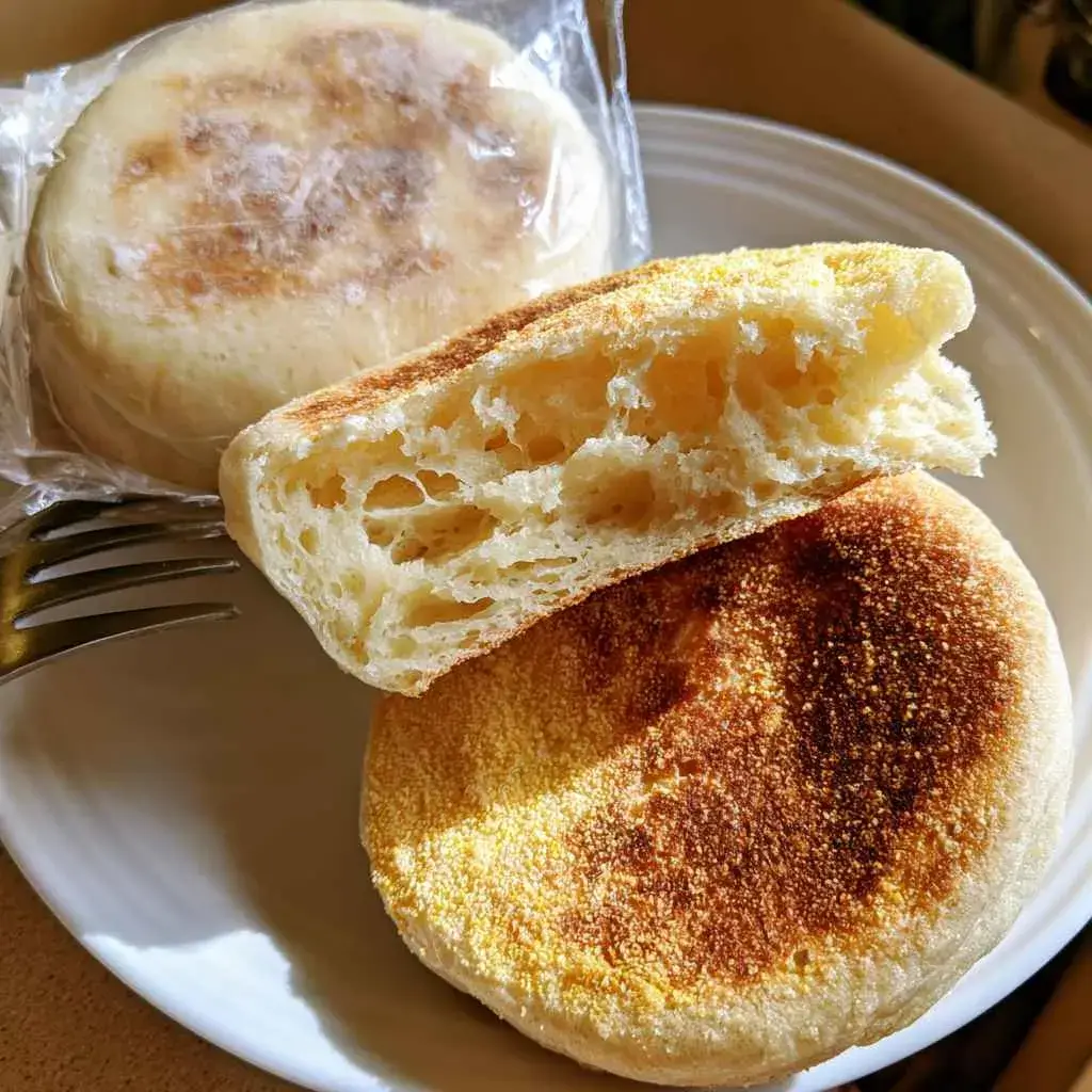 High protein english muffin split open beside a store-bought packaged muffin for a protein comparison