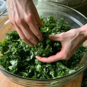 Hands massaging chopped kale with lemon for a high protein vegan salad